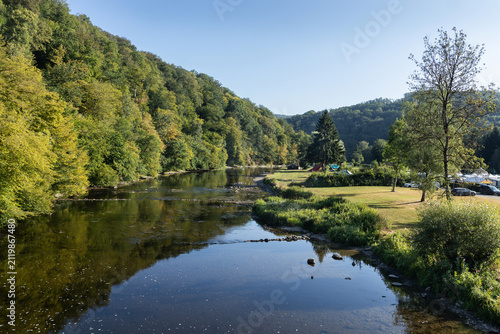 Early morning summer view of the beautiful Semois River as it flows through the village and campsites of the popular vacation destination of Membre, in Vresse-sur-Semois, Belgium. Copy space above.