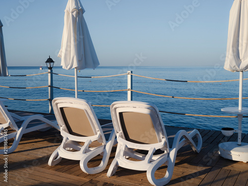 Fotografía Sun loungers and umbrellas on a wooden beach pier