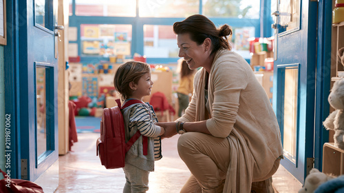 Kindergarten teacher greeting a young student. Preschool educator welcoming a child at school.