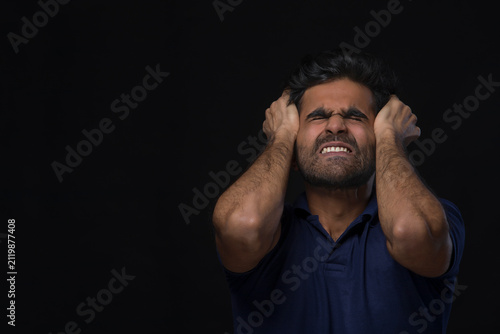 closeup of an angry man holding his head
