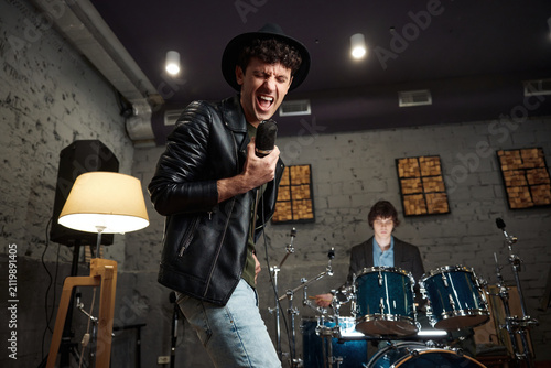 Konstfotografi Energetic singer gripping vintage microphone in gritty rehearsal studio