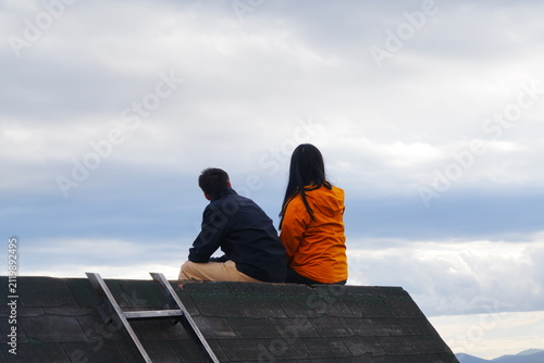  A young couple sat talking and flirting on the rooftop, happily enjoying the sky and the natural scenery.
