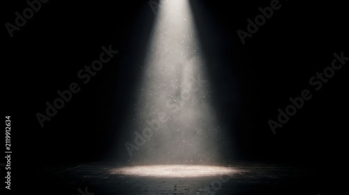 A single bright spotlight illuminates a dusty, dark stage, creating a dramatic and atmospheric scene