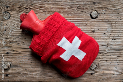 Hot water bottle in knitted sleeve with first aid symbol