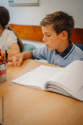 Картината върху платно Young boy learning at school desk during class