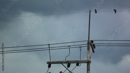 Foto The image features a section of electrical poles and wires set against a cloudy