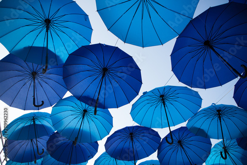 Blue and cyan umbrellas are arranged overhead in a bold geometric pattern, vibrant outdoor festival decoration, creative background.