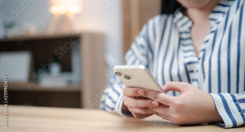 Business woman using a smartphone while working in a modern home office. Mobile technology, online communication