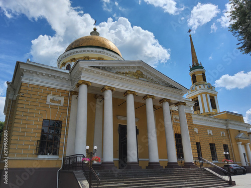 Exterior facade of Transfiguration Cathedral in classicism style with white columns and golden dome under blue sky in Dnipro, Ukraine.