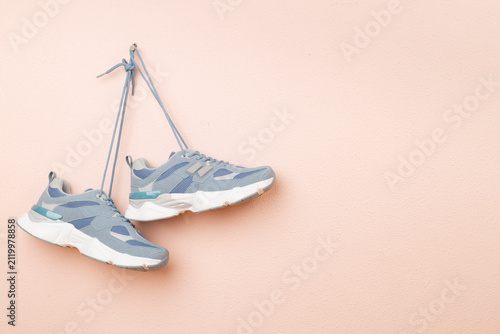 Pair of sneakers hanging on color wall