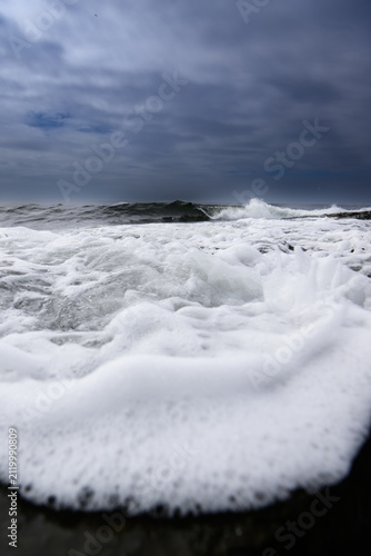 Stormy sea with big waves and foam on the shore