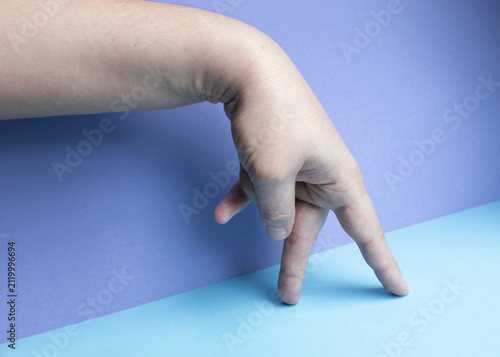 Canvastavla Close-up of a human hand with index and middle fingers extended downward against a purple and blue background, imitating walking legs and symbolizing motion, creativity, and playfulness