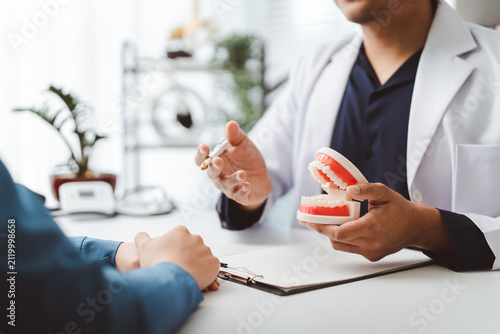 Cuadro en lienzo Dentist explaining complex dental procedure to patient, holding a jaw model and