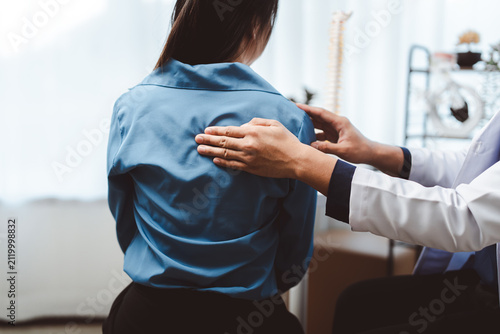 Doctor examining a patient's upper back, assessing for spinal issues and providing care for discomfort or injury, promoting health and wellness in a medical setting