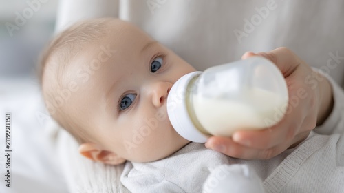 Adorable baby feeding: close-up of infant drinking from bottle in cozy setting