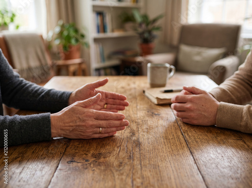 Therapy Session with Two People Holding Hands Across Wooden Table