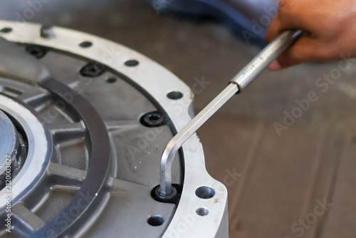Photography Close up of a mechanic tightening a bolt on an industrial machine component using an allen key