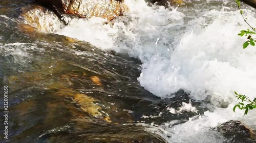 Real time video of a powerful turbulent stream of a mountain river with sound, where the current breaks off the rapids and splashes and white bubbles and foam are formed. Beautiful natural spaces