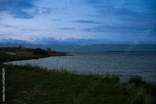 Tranquil Lakeside Cove in Blue Hour Twilight with Distant Clouds on Mountains