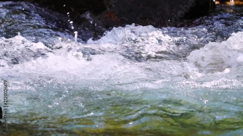 Realtime video of surface of a turbulent mountain river with clear, bluish water and a front view of the current side low angle view with sound of splashes. Soothing shots of nature, 120 fps full hd