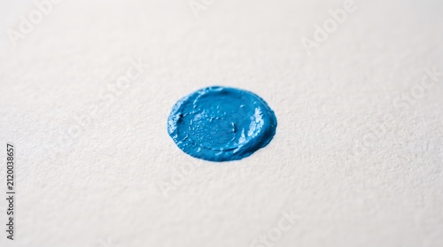 Close-up of blue paint dot on white paper. Artistic abstract background for creative projects.