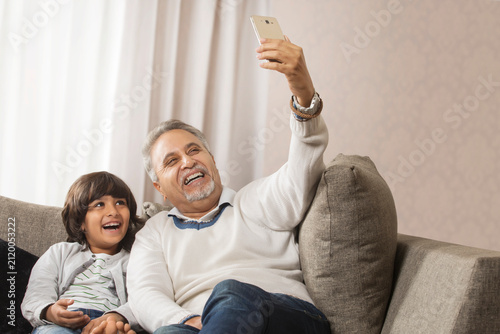 Photography Happy grandfather and grandson taking a selfie together sitting on sofa