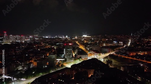 Night aerial footage of Bratislava, Slovakia, overlooking Trnavske myto and the illuminated city center in the direction of Bratislava Castle. The panoramic view captures major roads, modern buildings