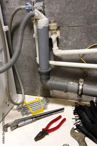 Vertical orientation plumbing tools wrench and pipes under bathroom sink installation or repair process water filtration system apartment maintenance sewage pipeline renovation home improvement handym