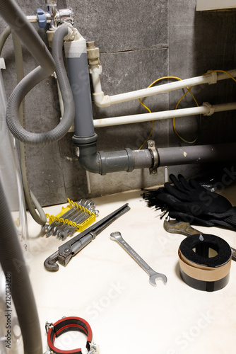 Foto Vertical orientation plumbing tools wrench and pipes under bathroom sink install