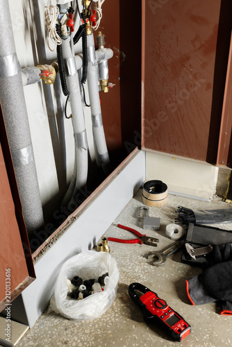 Vertical orientation plumbing tools and fittings on floor near heating collector pipes system installation apartment maintenance or repair process water utility infrastructure renovation