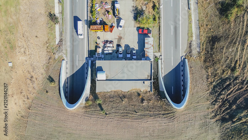 Top down aerial view of twin highway tunnel entrance portals with maintenance yard and parked vehicles in Greece for infrastructure transportation stock photo