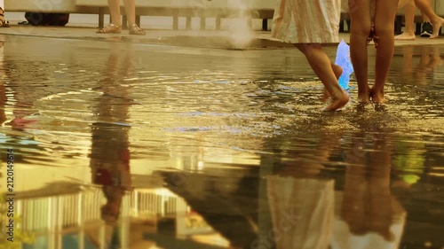 Bare feet cooling in an illuminated urban fountain during summer heat