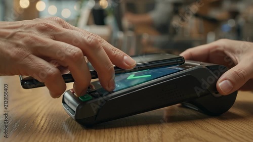 Customer paying with smartphone on credit card terminal at coffee shop counter