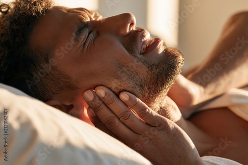 Close up of a man suffering from jaw pain after sleep due to bruxism, highlighting teeth grinding, TMJ disorder, facial muscle tension and dental health problems