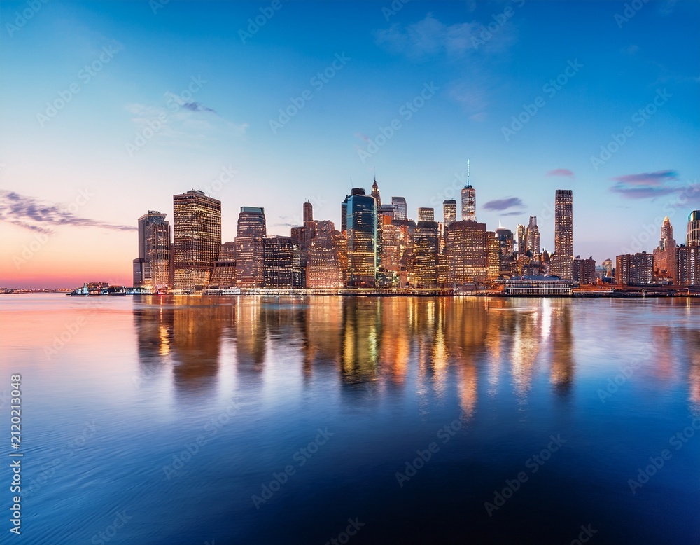 Naklejka premium panoramic view of new york city skyline at dusk with calm water reflection