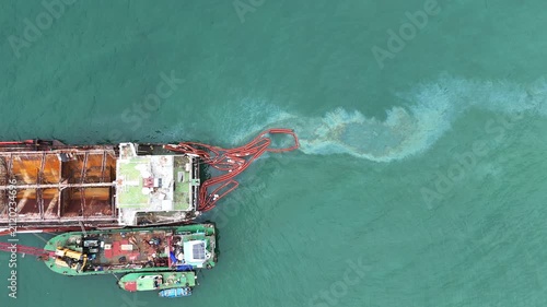 Oil spill Industrial response ship deploying an orange containment boom to control and clean up a marine pollution spill in the open ocean, protecting the sea ecosystem from hazardous chemical waste.