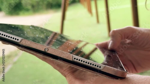 Woman Using a Tablet with Raindrops on the Screen Outdoors