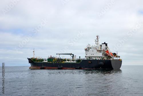 Foto Ein Frachtschiff liegt auf ruhiger See unter bewölktem Himmel vor Swakopmund, Namibia