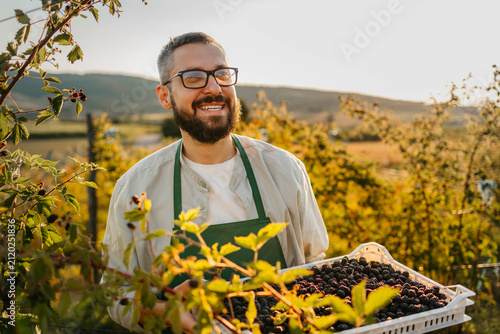 Young Handsome Farmer Holding a Basket of Ripe Blackberries