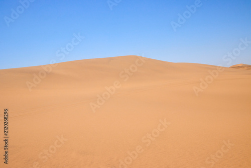 Eine einzelne hohe Sanddüne steht unter klarem Himmel in der Wüste bei Swakopmund in der Region Erongo, Namibia.