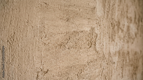 Extreme close-up macro of raw lime-washed plaster wall, warm clay tone, visible brush stroke texture