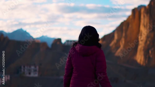 Rear view of Indian female tourist walking in front of Dhankar Monastery in Spiti Valley, Himachal Pradesh, India. Young Indian woman travel and explore mountains. Travel lifestyle, budget trip and ba