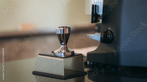 Quadro su tela Shiny coffee tamper sits on a dark surface