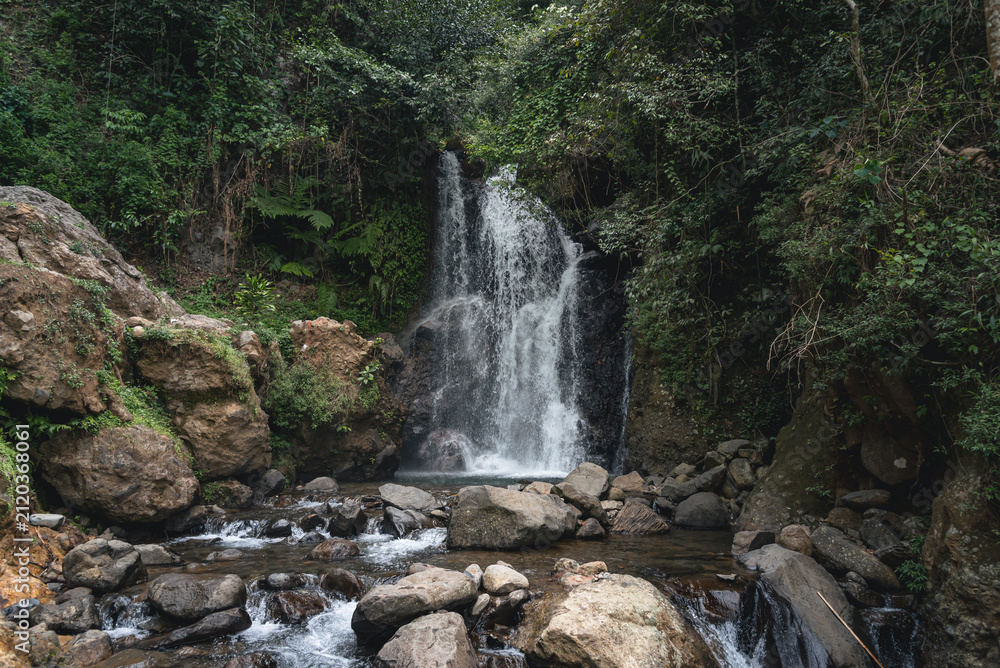 Obraz premium Beautiful Cipamingkis Waterfall surrounded by lush tropical forest in Bogor, West Java, Indonesia, ideal for travel, nature, and ecotourism concepts