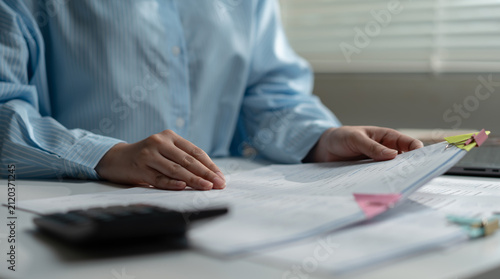 Businesswoman reviewing financial documents, audit reports, and accounting records on office desk. Financial analysis, bookkeeping, compliance, budget planning, tax preparation, and corporate finance.