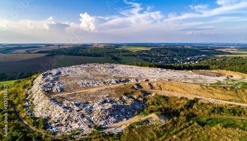 Large Rural Landfill Spreading Across Green Countryside Under Blue Sky