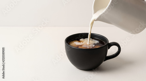 Creamer poured into black coffee, cozy atmosphere, minimalistic background, copy space
