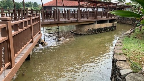 Wooden pedestrian bridge crossing a landscaped waterway within a park setting Botanical Putrajaya, Malaysia