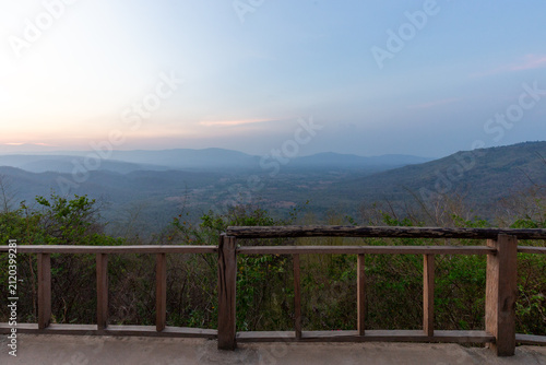 Obraz na plátně Wooden balcony viewpoint overlooking a vast misty mountain valley and distant hi