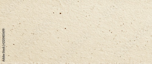 Close-up textured surface of pale, off-white material with small, dark speckles